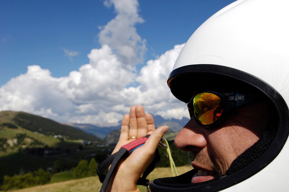 Ein Mann mit Helm hält Gleitschirm, Seiser Alm, Eisacktal, Südtirol, Italien, Europa