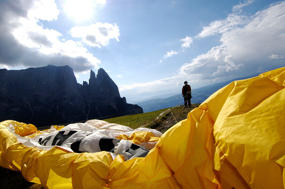 Eine Person mit Gleitschirm steht vor einem Abhang, Seiser Alm, Eisacktal, Südtirol, Italien, Europa