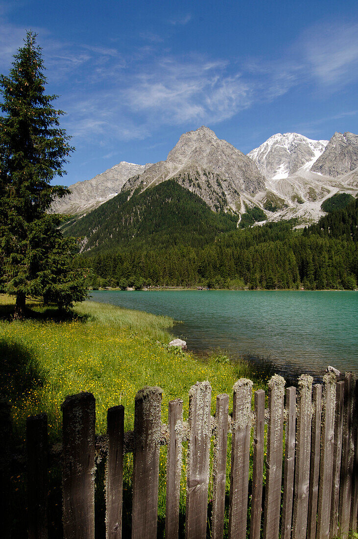 Wooden fence in front of the Antholzer lake in idyllic mountain scenery in the sunlight, Val Pusteria, South Tyrol, Italy, Europe