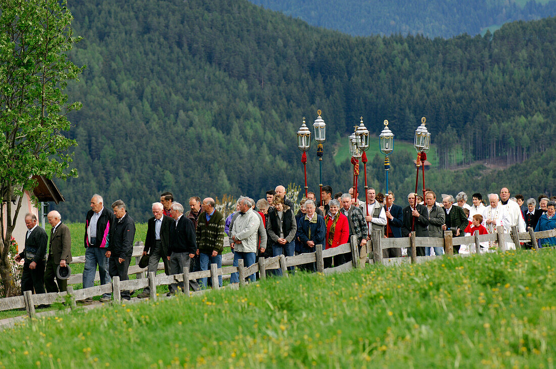 Menschen gehen in einer Prozession auf einem Weg in grüner Landschaft, Kastelruth, Eisacktal, Südtirol, Italien, Europa