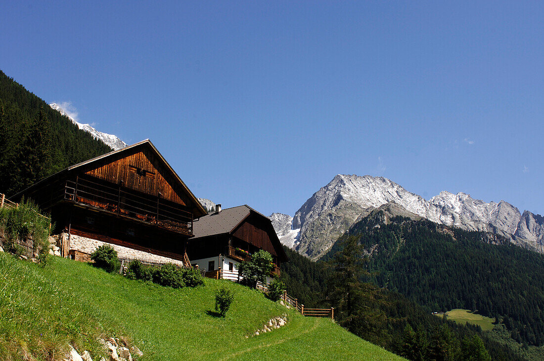 Bauernhaus mit Scheune in den Bergen unter blauem Himmel, Pustertal, Südtirol, Italien, Europa