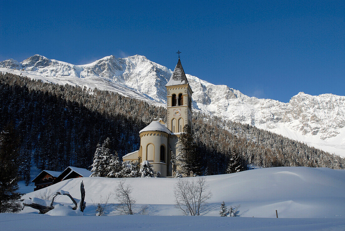 Die Kirche St. Gertaud vor schneebedeckten Bergen unter blauem Himmel, Sulden, Vinschgau, Südtirol, Italien, Europa