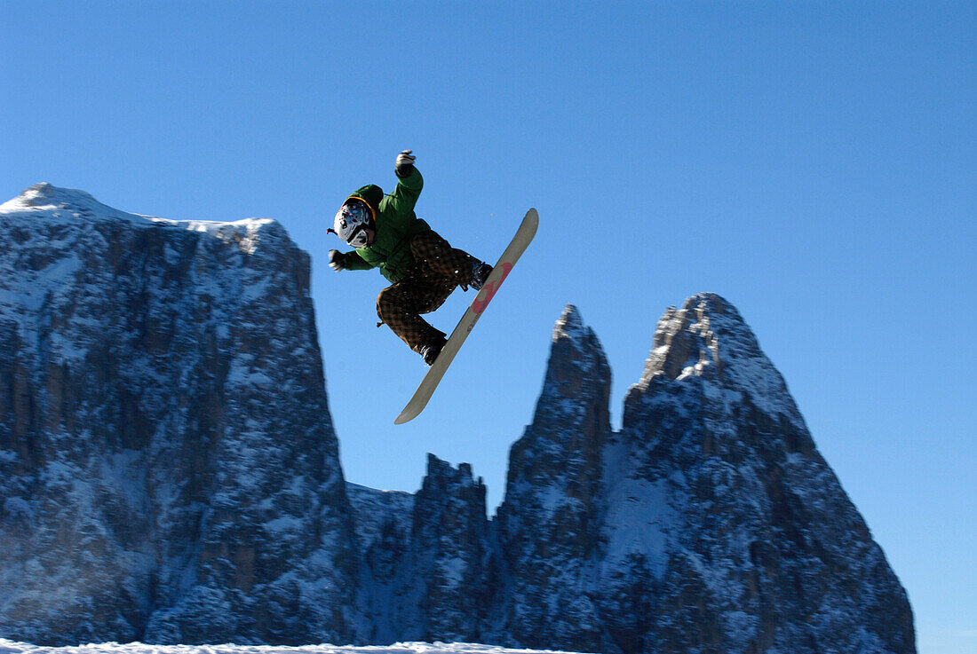Ein Snowboarder im Sprung vor Bergen und blauem Himmel, Dolomiten, Südtirol, Italien, Europa