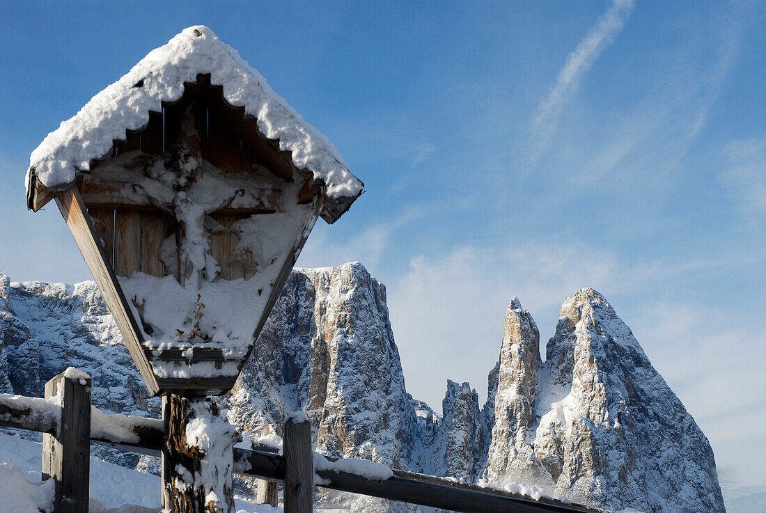Snow covered wayside cross in front of snowy mountains, Alpe di Siusi, South Tyrol, Italy, Europe