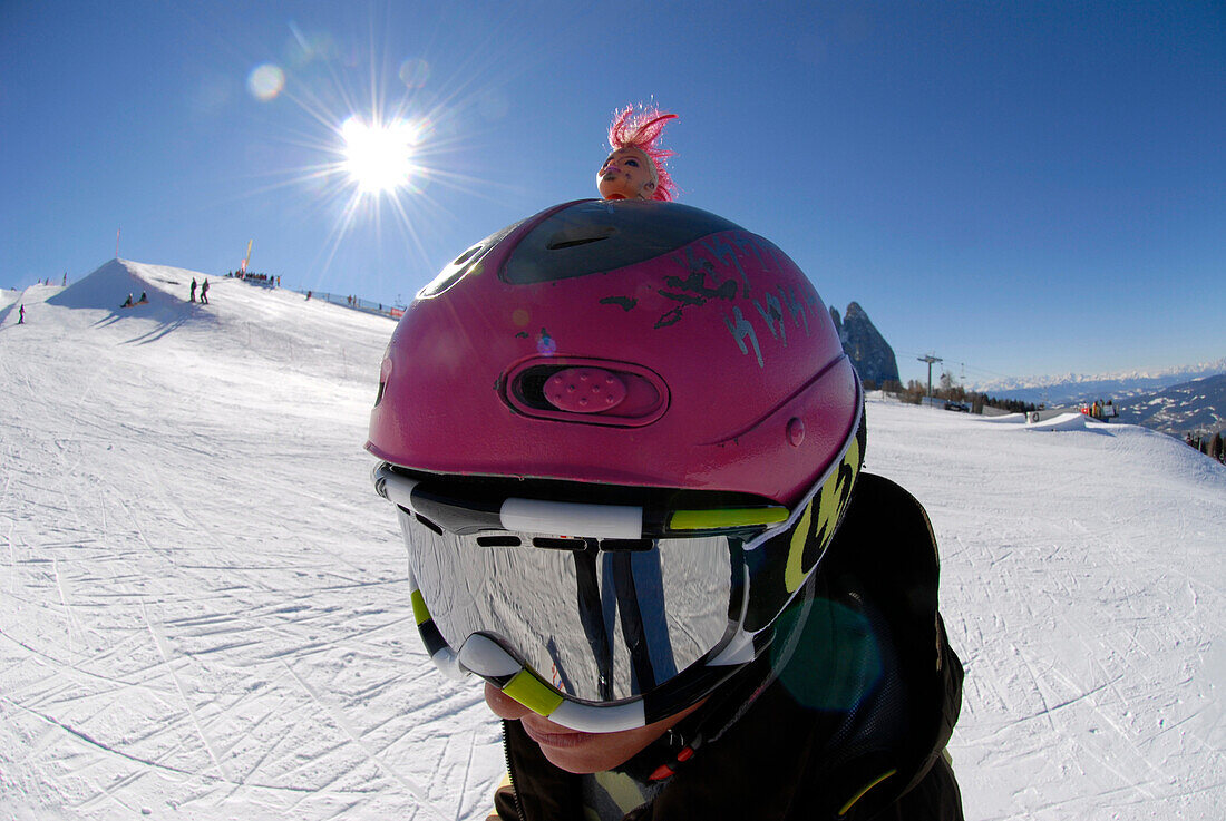 A teenager wearing a helmet and ski goggles in front of sunlit ski slope, South Tyrol, Italy, Europe