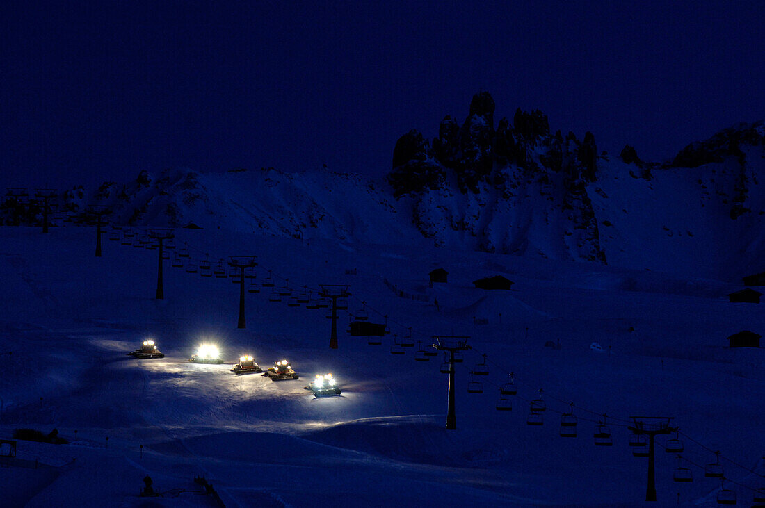 Caterpillars treating the ski slope at night, South Tyrol, Italy, Europe