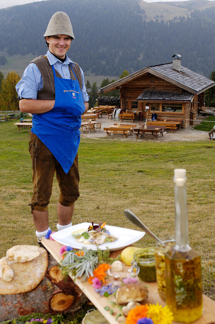 Lachender Mann und Essen im Freien vor einer Almhütte, Seiser Alm, Südtirol, Italien, Europa