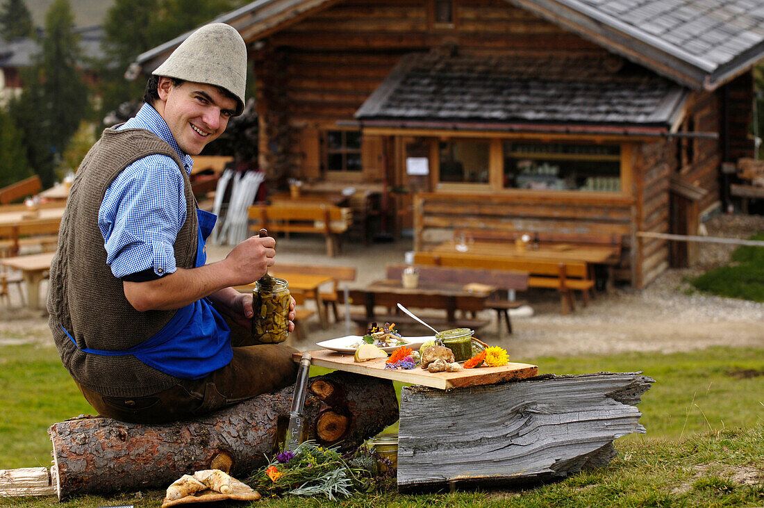 Laughing man sitting in front of an alpine hut, Gostner Schwaige, Alpe di Siusi, South Tyrol, Italy, Europe