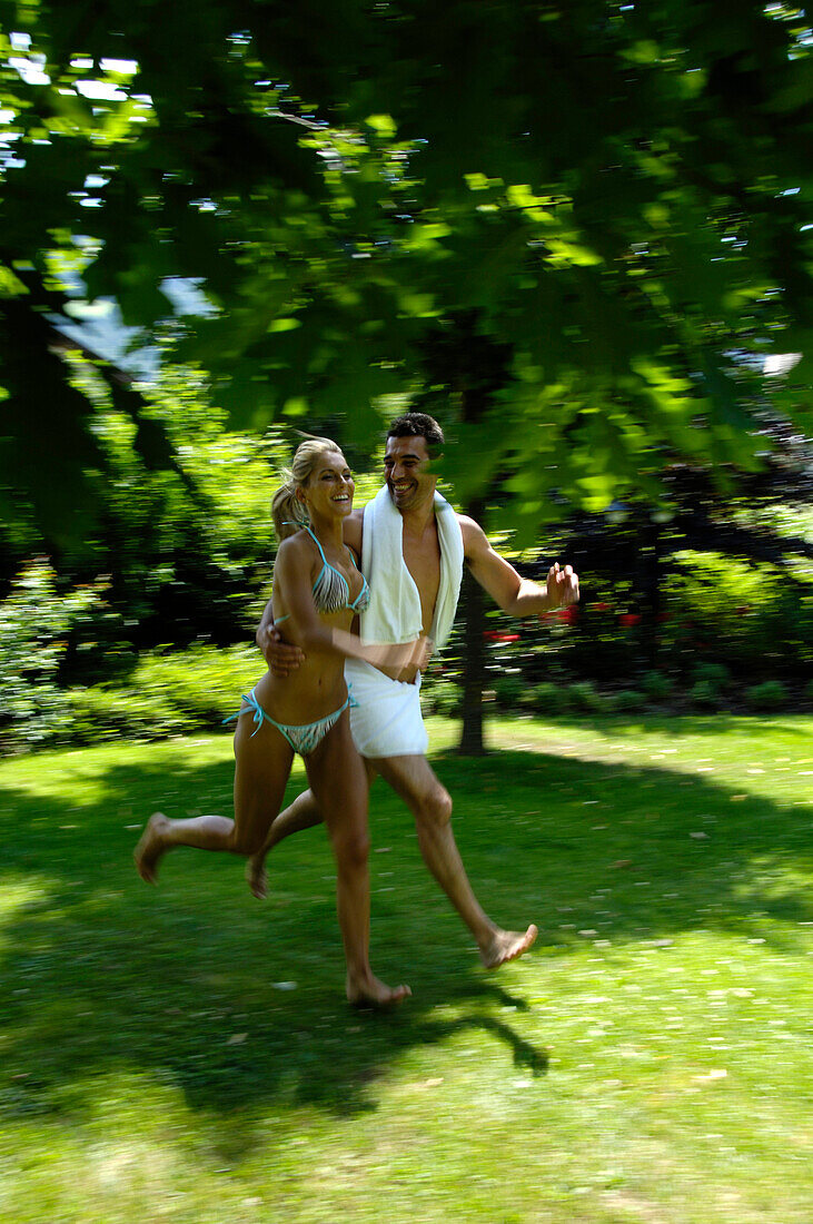 A young couple running accross the grass, Motion, Park, South Tyrol, Italy