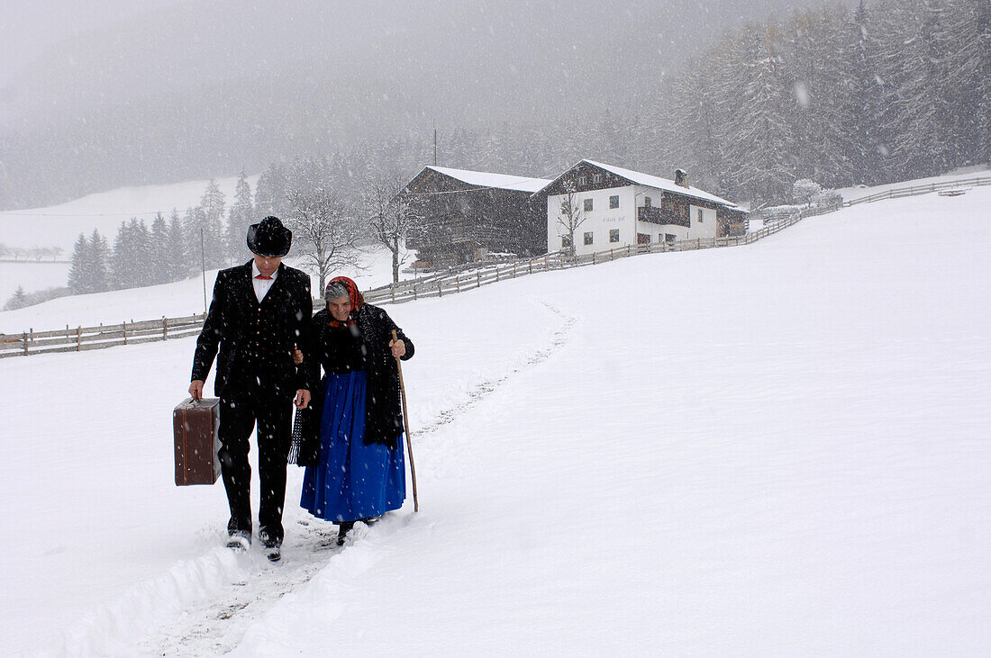 Farmer and mother walking through the snow away from farmhouse, Agriculture, South Tyrol, Italy