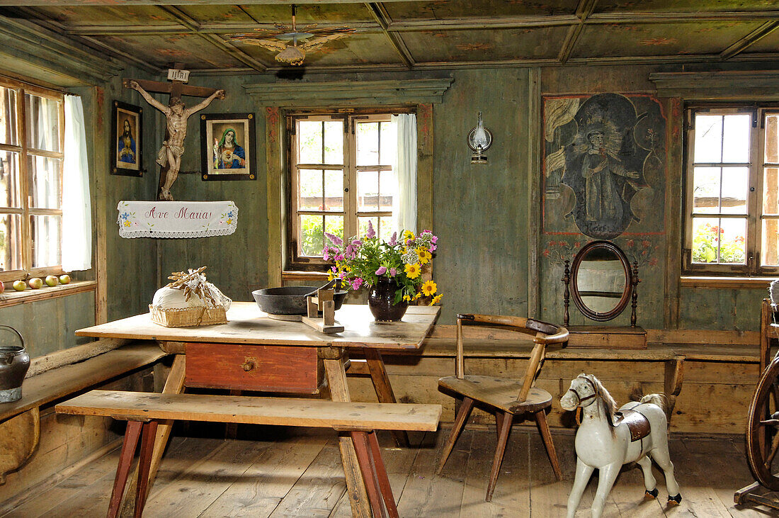 View inside the farmhouse with wooden bench, table and rocking horse, South Tyrolean local history museum at Dietenheim, Puster Valley, South Tyrol, Italy