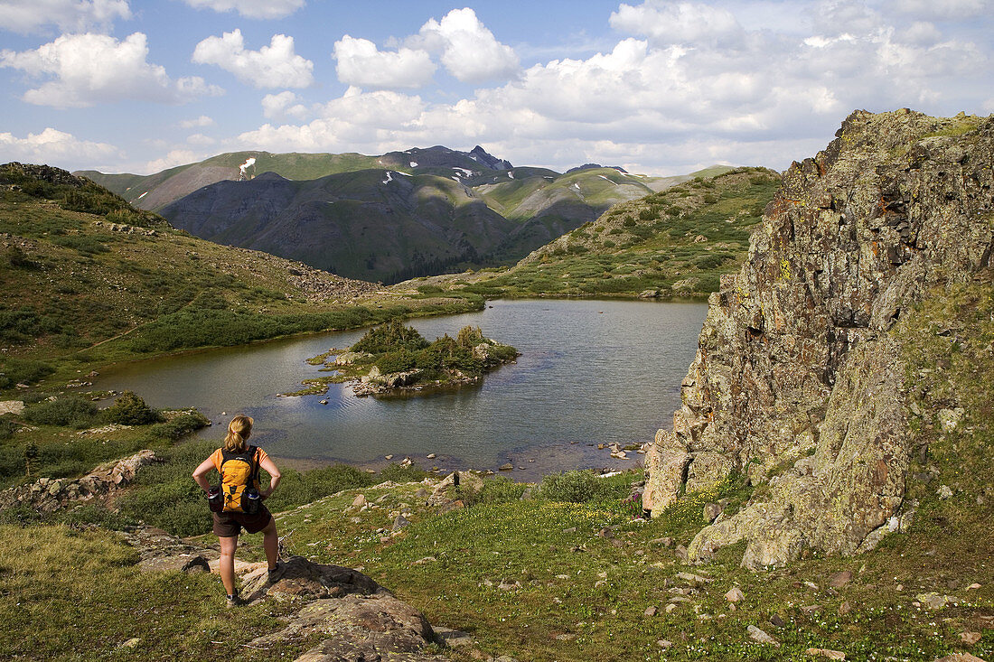 Female hiker pauses to take in the view above Highland Mary Lakes in the Weminuche Wilderness, San Juan Mountains, Colorado, USA