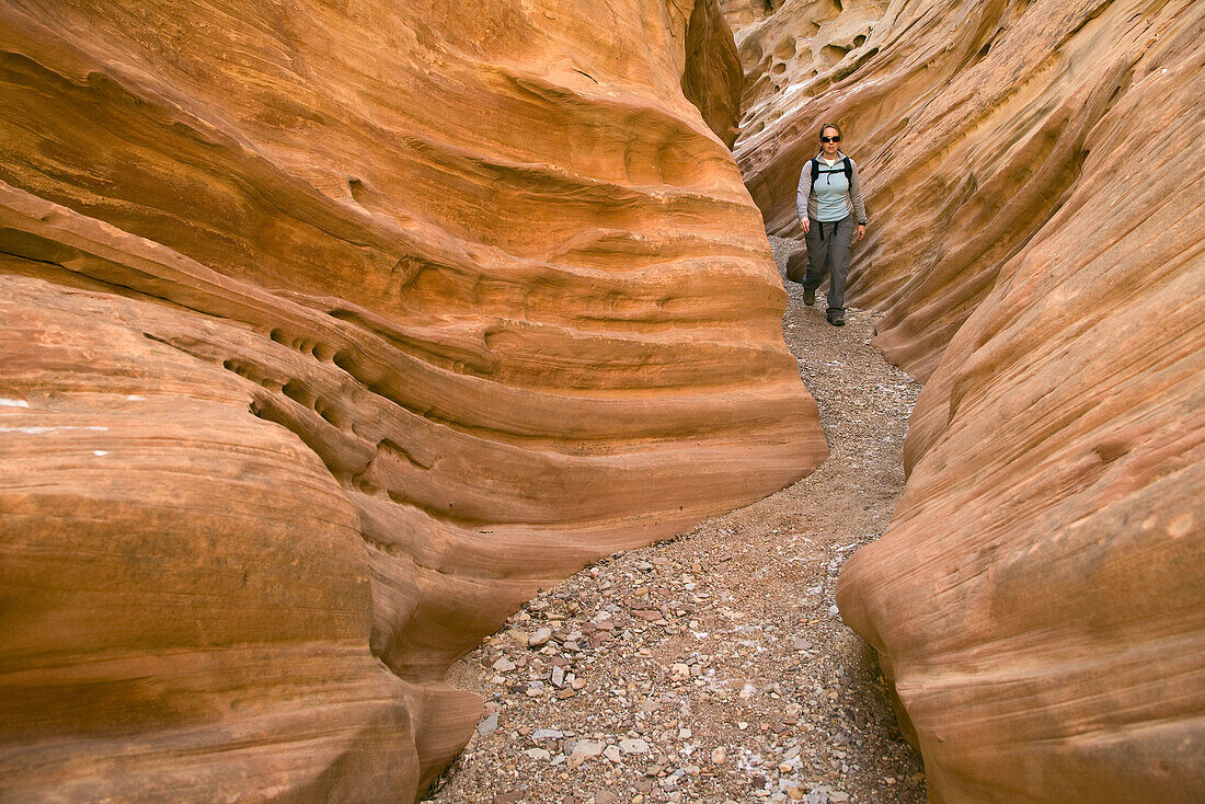 Female hiker walks through a ribbed section of sandstone in Little Wildhorse Slot Canyon, San Rafael Swell, Utah, USA