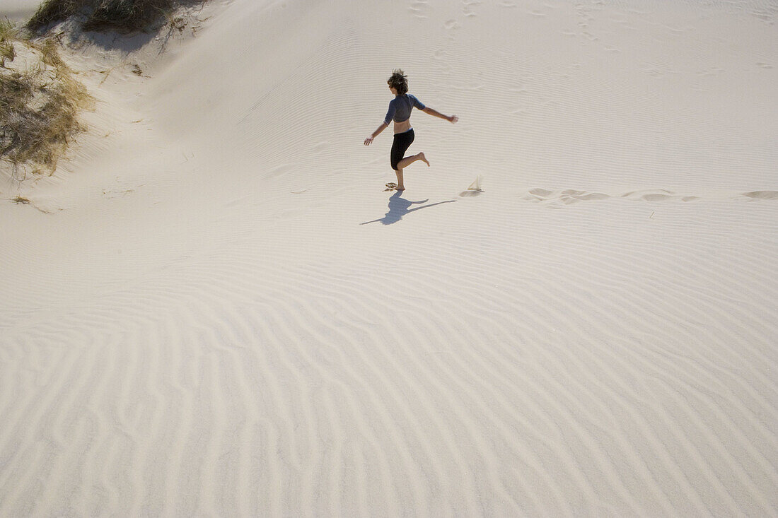 Girl runs, in the sand dunes