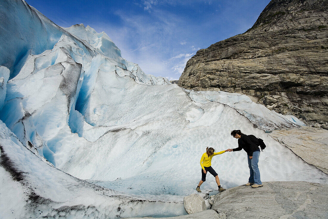 Woman helping another one in Jostedalsbreen glacier (Nigardsbreen). Sogn og Fjordane. Norway.