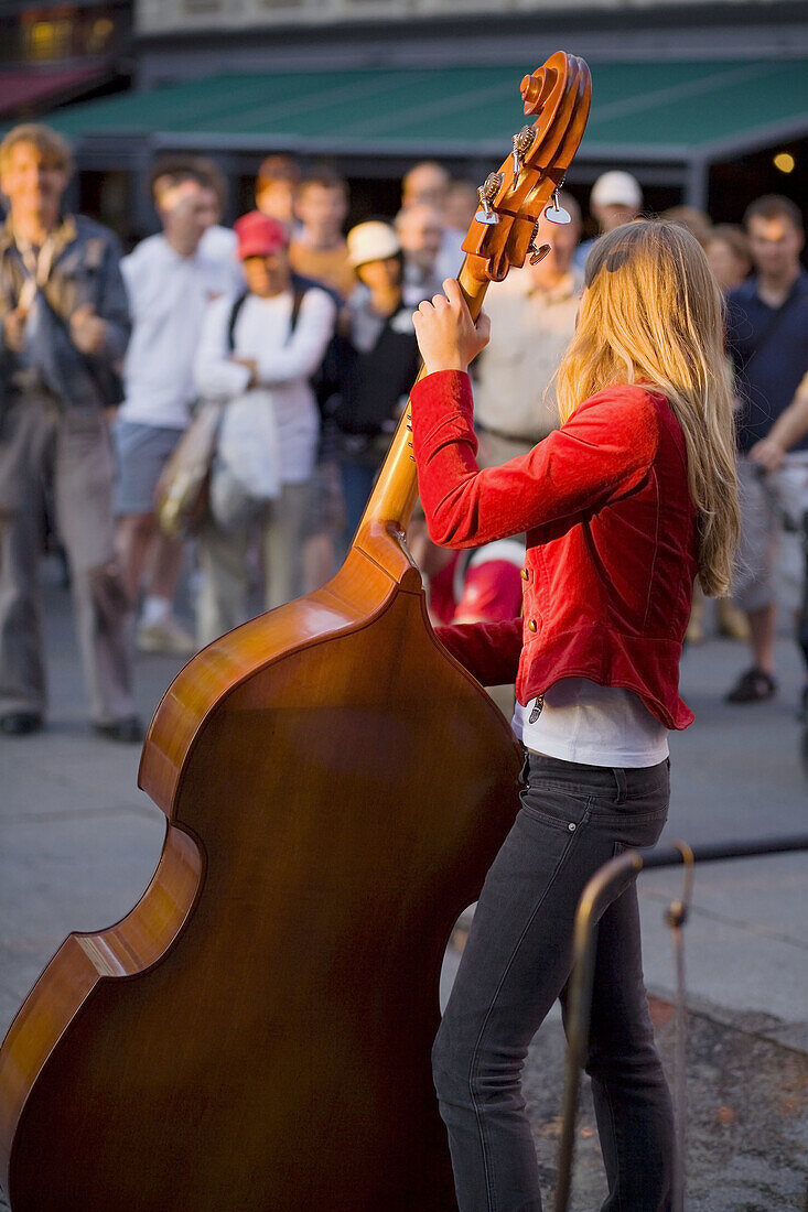 Young woman playing double bass in a centric street. Oslo. Norway.