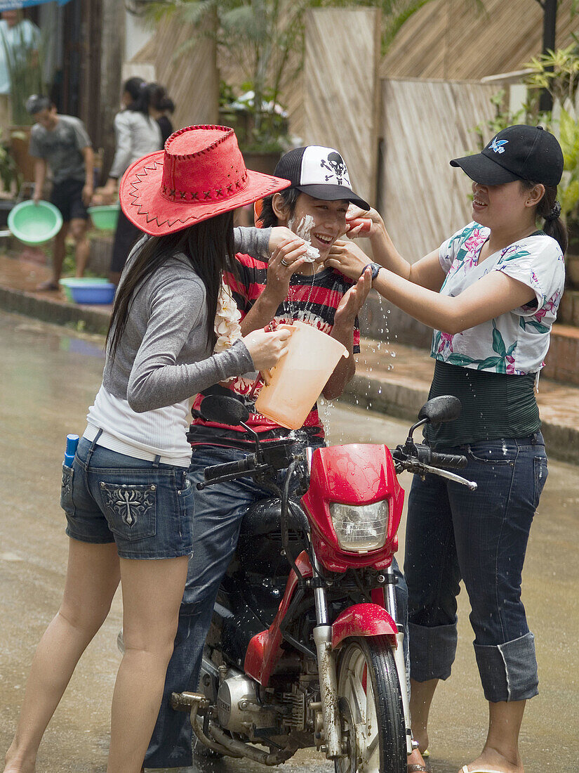 Young women stop a motorcyclist to drench him during Lao New Year, Luang Prabang
