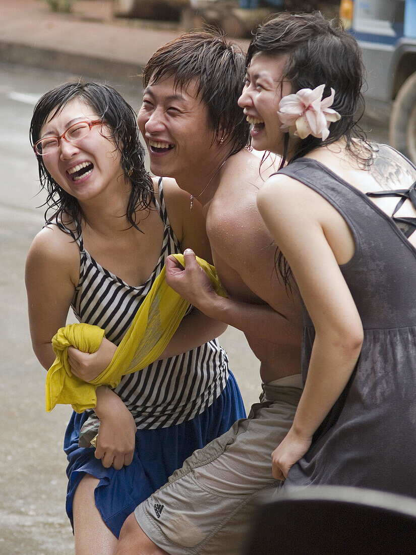 3 Chinese tourists laugh during the wild and wet Songkran Lao New Year Festival, Luang Prabang, Laos