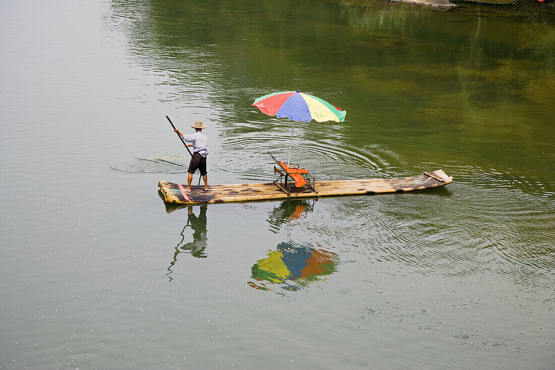 Boat man and his bamboo raft on the Yulong River in Guilin, China