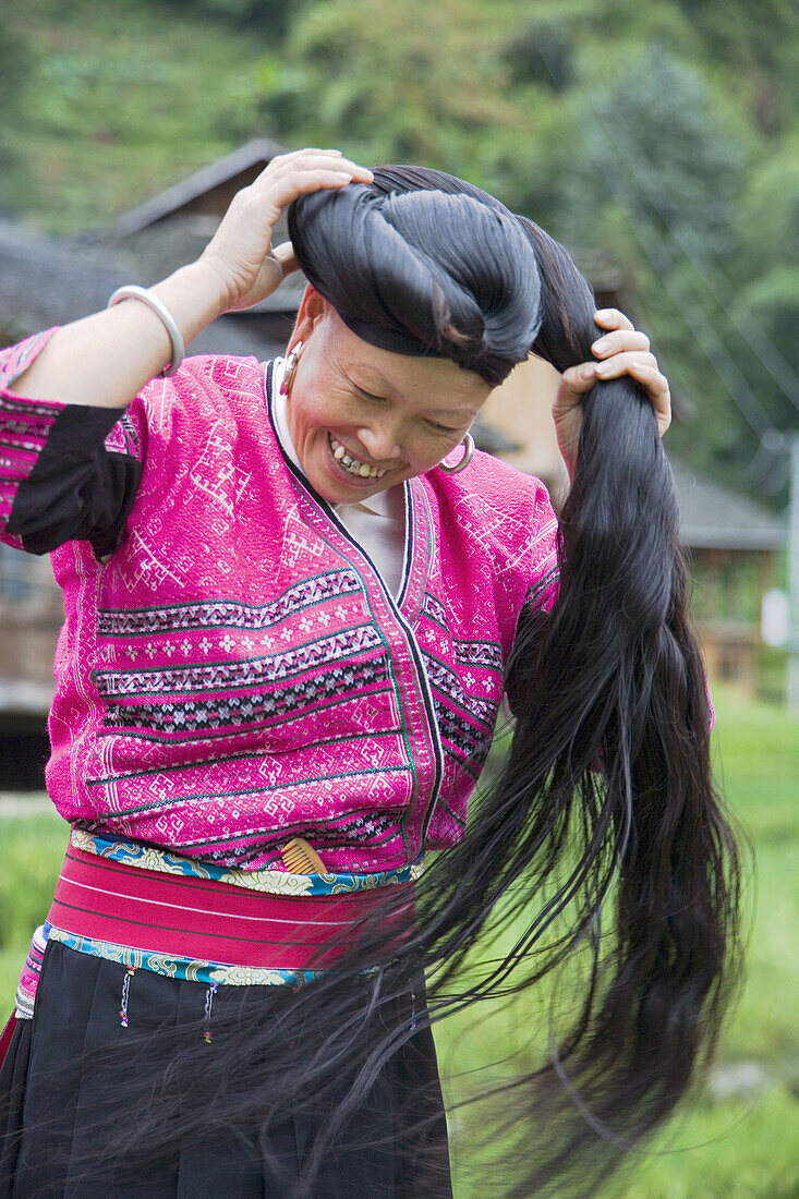 Long Haired Yao woman coiling her hair, a tradition kept by the Red Yao near Guilin, China