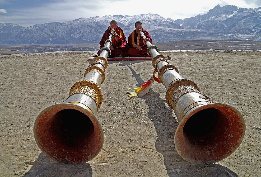 two monks playing the long tibetan Ragdun - horn on the roof of the Garze monastery, Sichuan, China