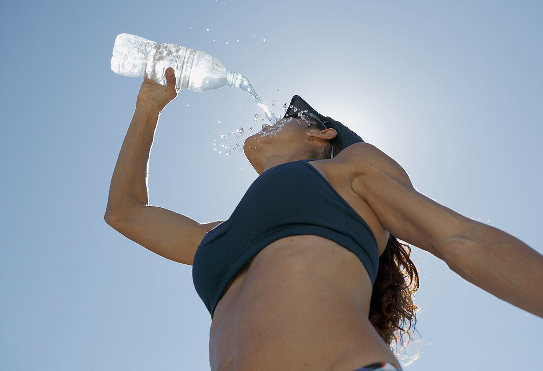 Woman athlete pours water on her face