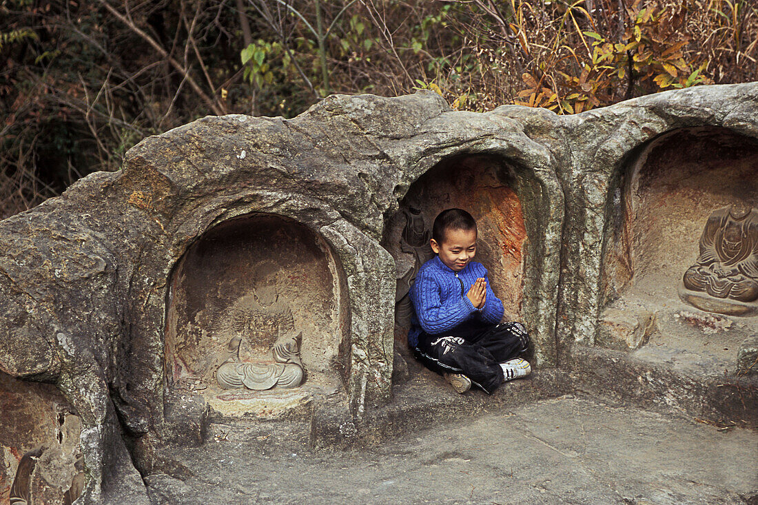 A young boy enjoys the moment in one of the many caves in Qi Xia temple near Nanjing China. Many of the Buddha statues in Qi Xia were destroyed in the culture revolution.