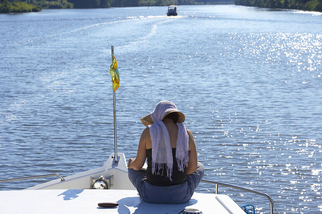 Frau sitzt auf einem Boot und liest, Havel bei Ketzin, Brandenburg, Deutschland