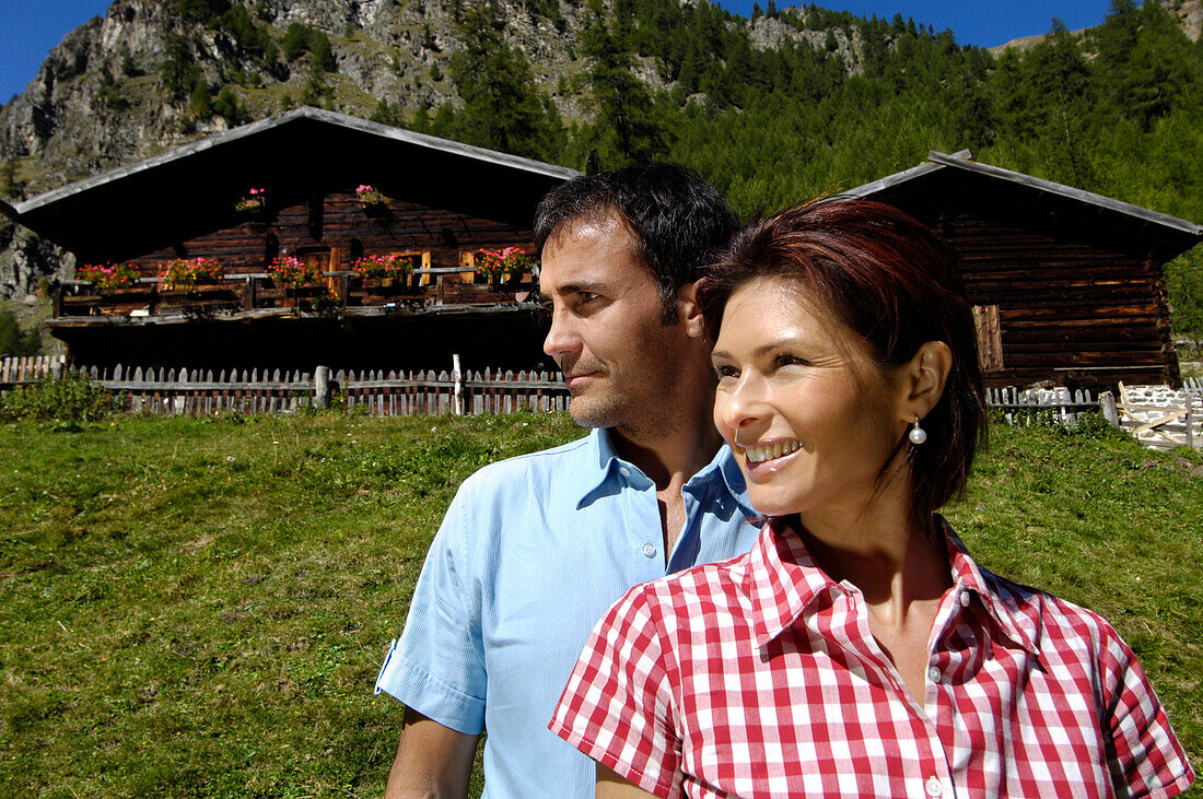 Mann und lächelnde Frau vor Almhütten im Sonnenlicht, Mastaun Alm, Schnalstal, Vinschgau, Südtirol, Italien, Europa
