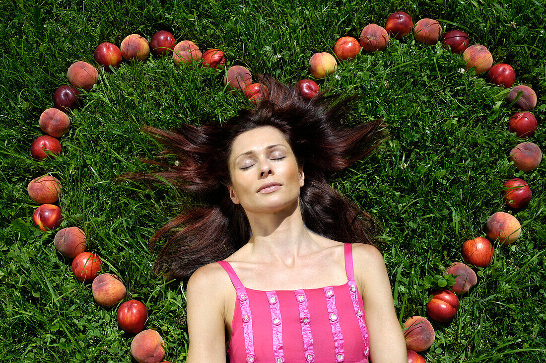 Eine Frau liegt in einem Herz aus Obst auf einer Wiese, Südtirol, Italien, Europa