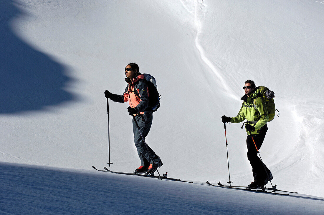 Zwei Langläufer beim Aufstieg im Sonnenlicht, Schnalstal, Vinschgau, Südtirol, Italien, Europa