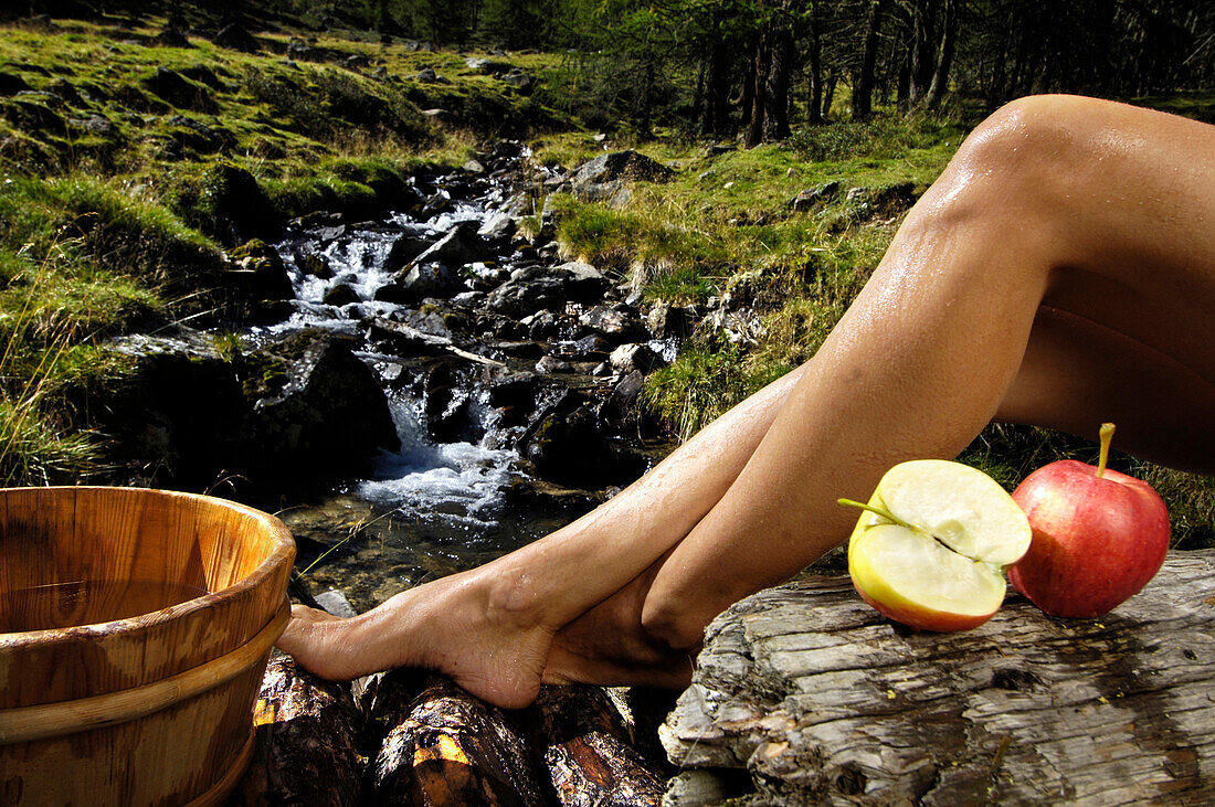 Äpfel und die Beine einer Frau an einem Bach im Sonnenlicht, Naturns, Mastaun, Schnalstal, Vinschgau, Südtirol, Italien, Europa