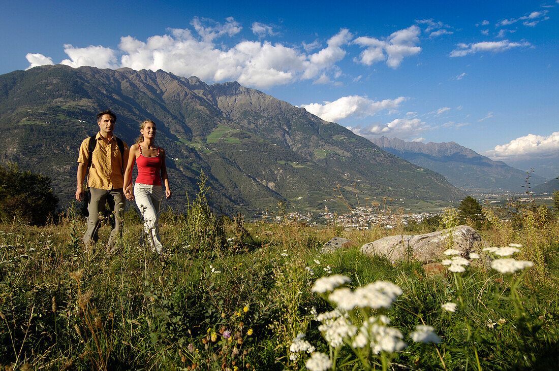Junges Paar wandert über eine Wiese in einem Tal, Naturns, Vinschgau, Südtirol, Italien, Europa