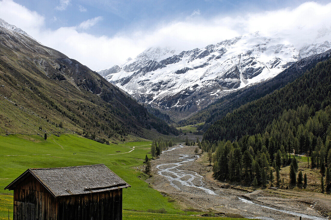 Schneebedeckte Berggipfel über Almhütte und Karlinbach im Frühling, Vinschgau, Südtirol, Italien, Europa