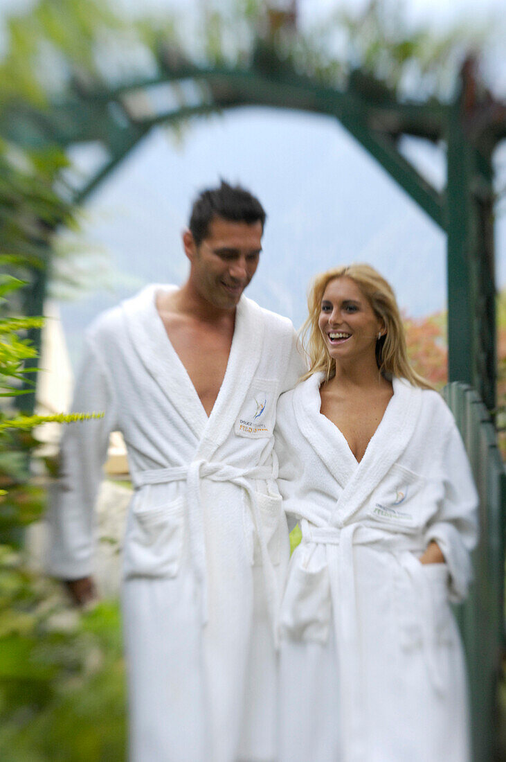 Young couple wearing bathrobes at the garden of a hotel, South Tyrol, Italy, Europe