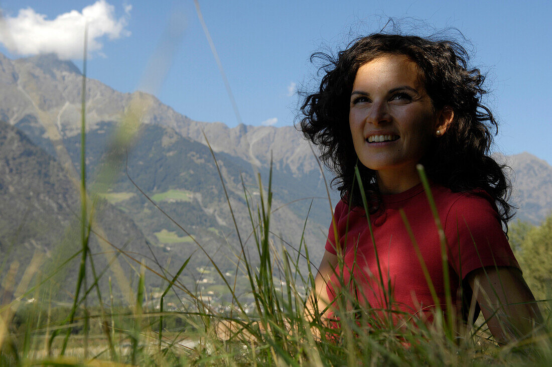 Junge Frau sitzt auf einer Almwiese, Vinschgau, Südtirol, Italien, Europa