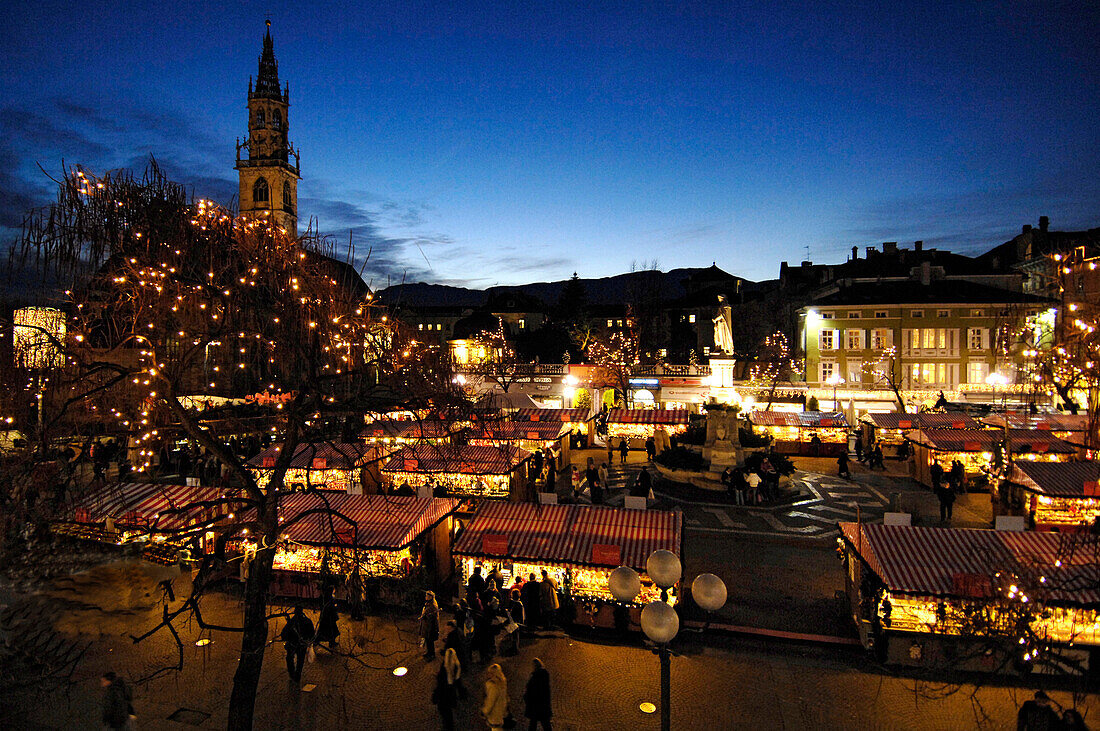 Christmas market at Walther square in the evening, Bozen cathedral in the background, Bolzano, South Tyrol, Italy