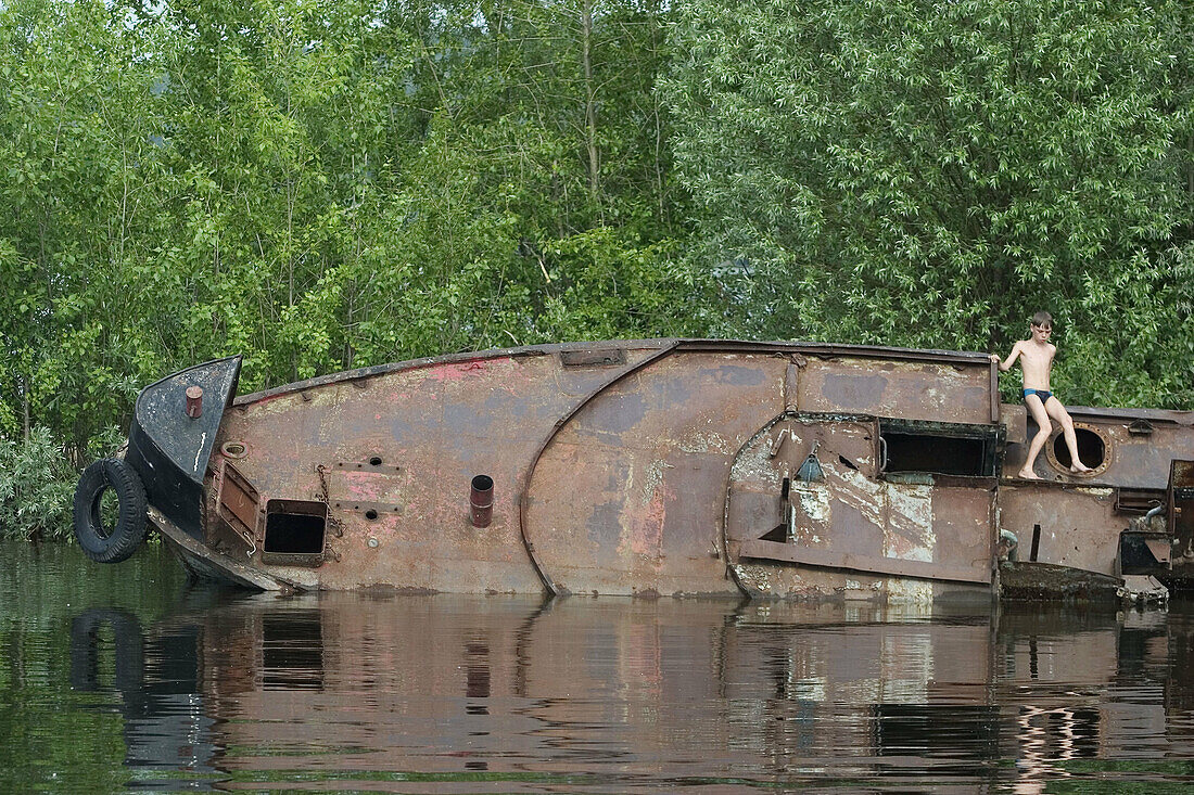 A child plays in a sunk ship on the Volga river. Tolyatti. Samara Oblast, Russia