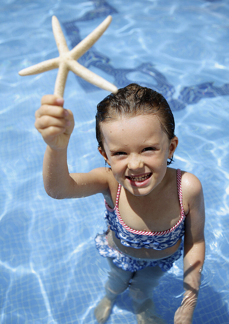 4 year old girl holding starfish.