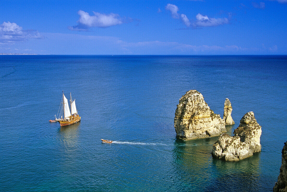 A sailing ship off a rocky coast in the sunlight, Ponta da Piedade, Algarve, Portugal, Europe