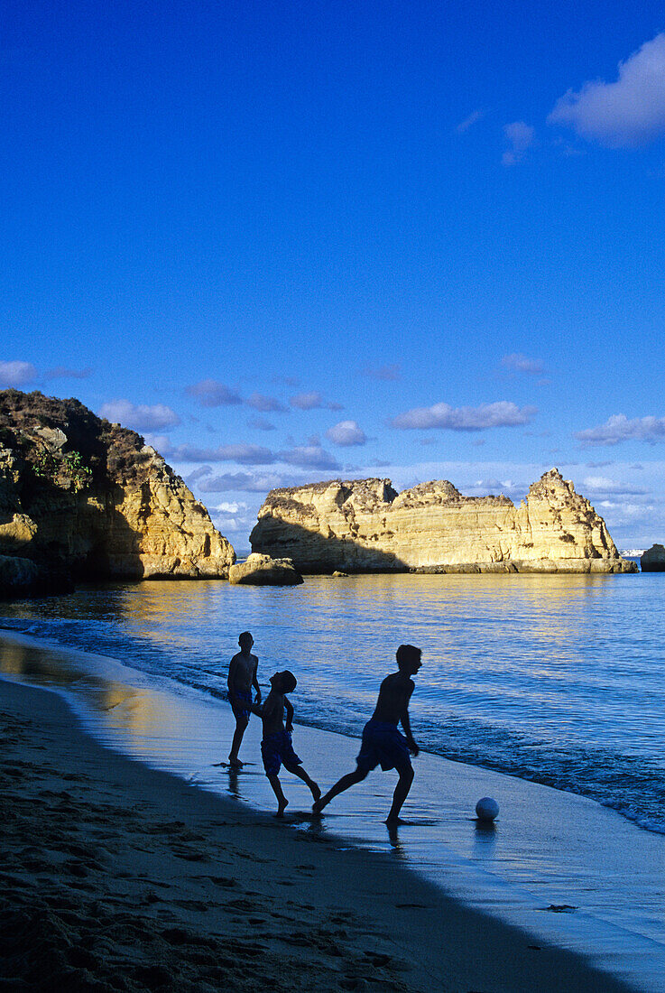Children playing football on the beach, Praia de Dona Ana, Algarve, Portugal, Europe