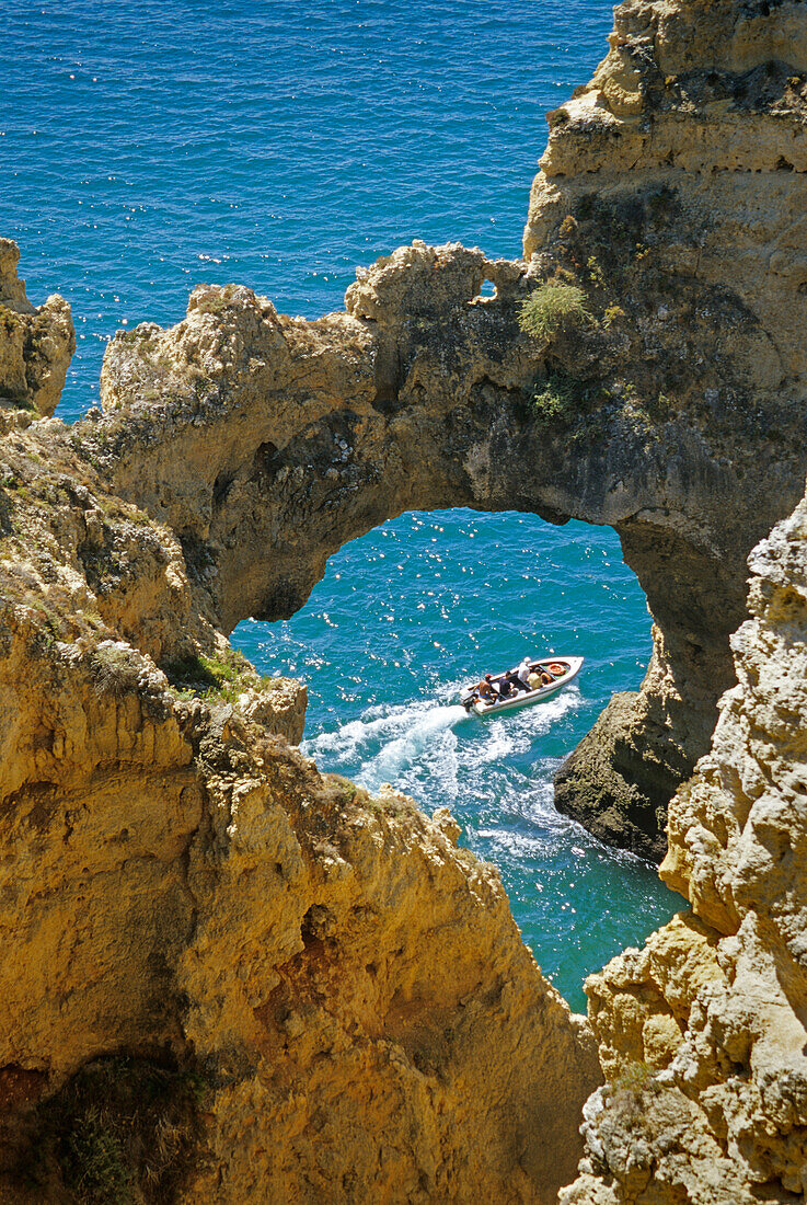 View through a rock arch at a motor boat, Ponta da Piedade, Algarve, Portugal, Europe