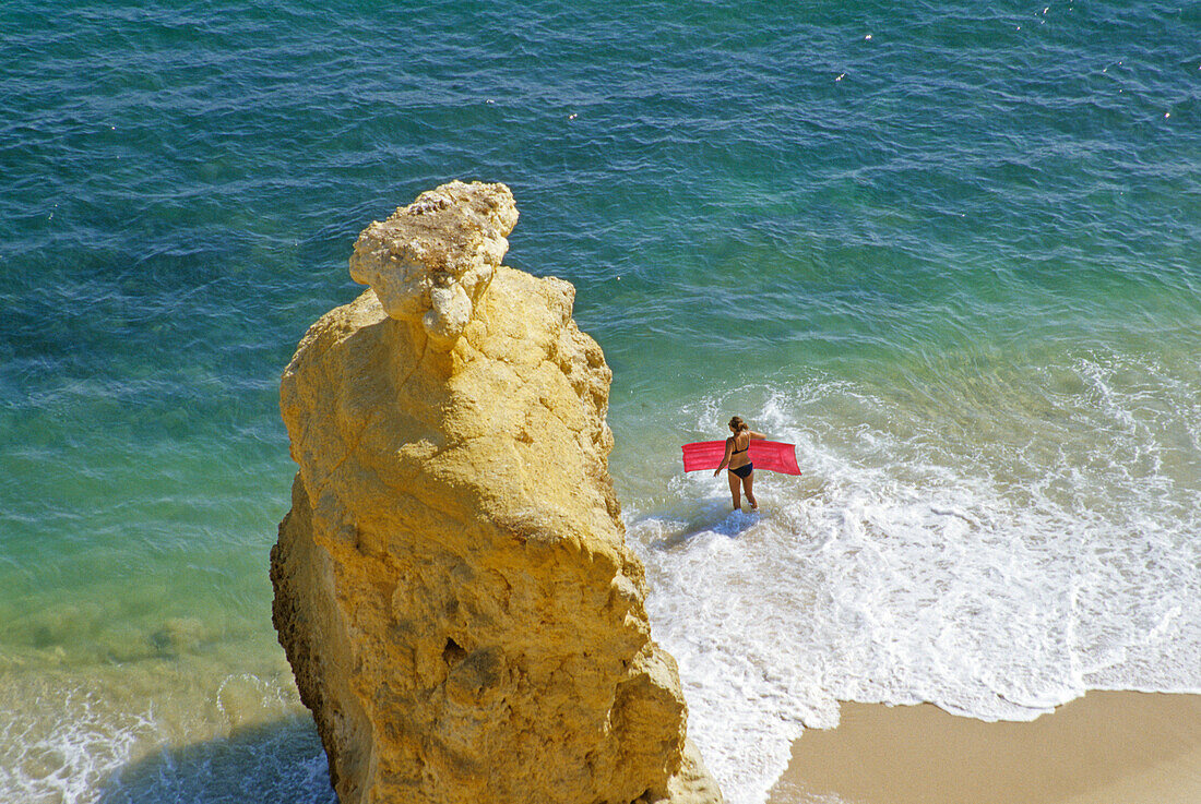 Blick auf Strand und Frau mit Luftmatratze am Wasserrand, Praia da Marinha, Algarve, Portugal, Europa