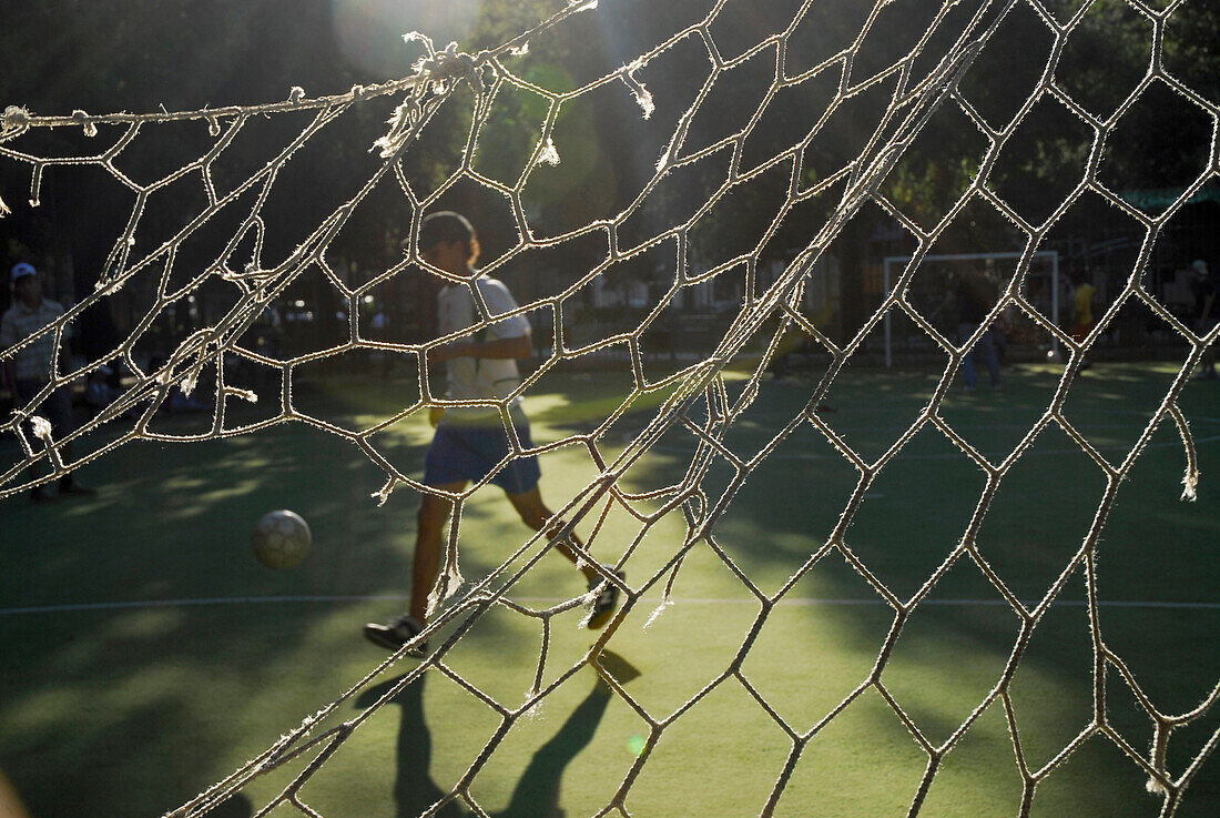 Blick durch zerrissenes Netz auf Fussballspiel im Park, Florenz, Toskana, Italien, Europa