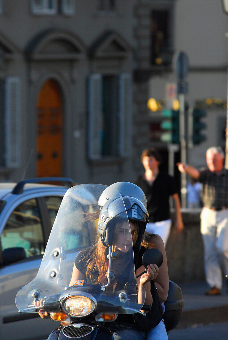 Frau auf Motorroller schaut in Rückspiegel, Ponte Santa Trinita, Florenz, Toskana, Italien, Europa