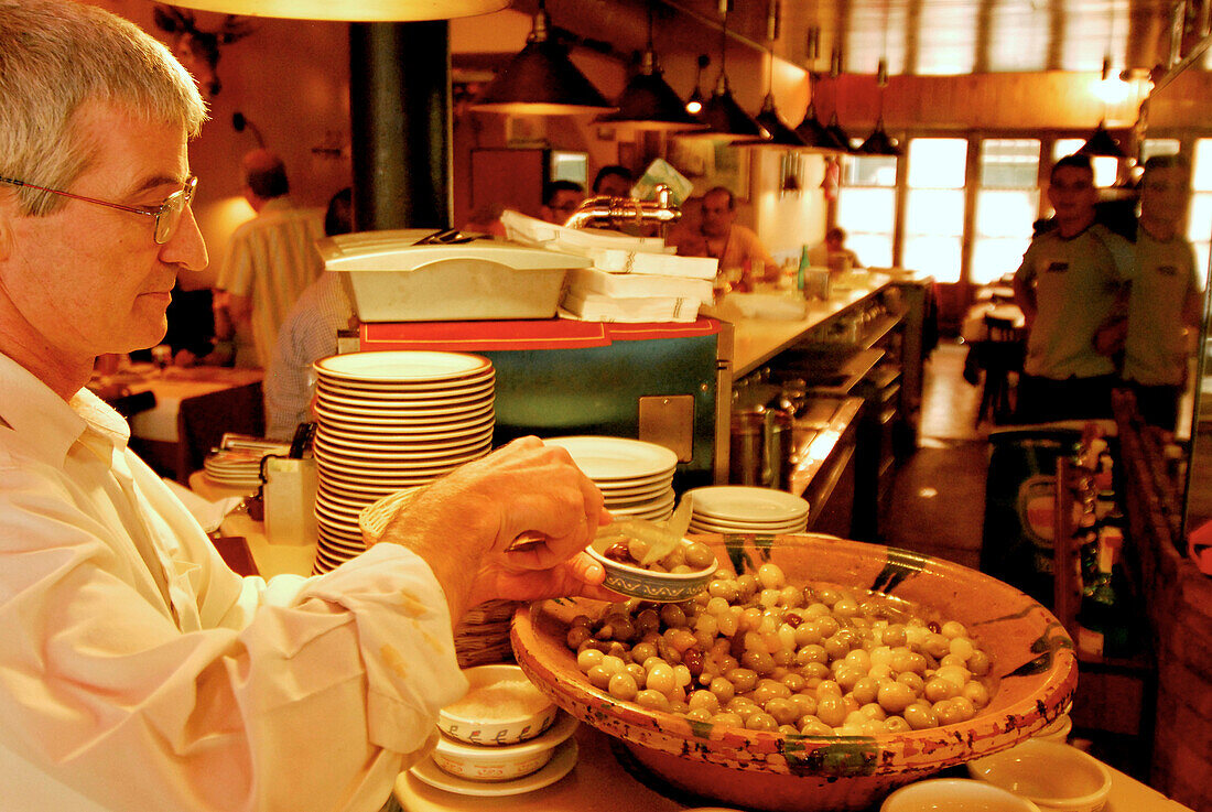 Owner Juan Hurtado placing olives on a plate, restaurant Pa amb Oli, Ciutadella, Minorca, Balearic Islands, Spain