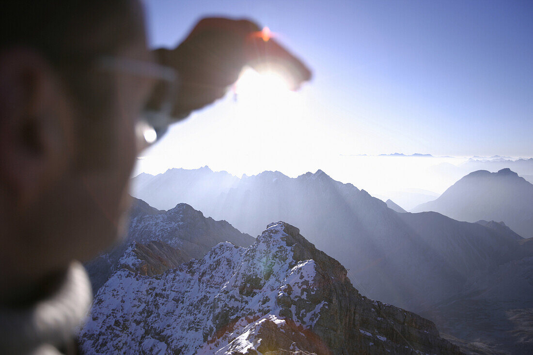 Mann auf der Zugspitze blickt in die Sonne, Bayern, Deutschland