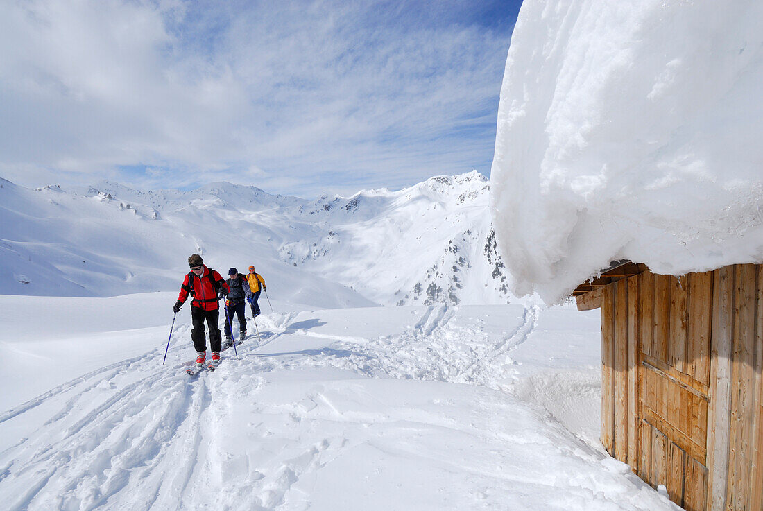 Backcountry skiers reaching snow-covered alpine hut, Marchkopf, Hochfuegen, Zillertal, Tyrol, Austria