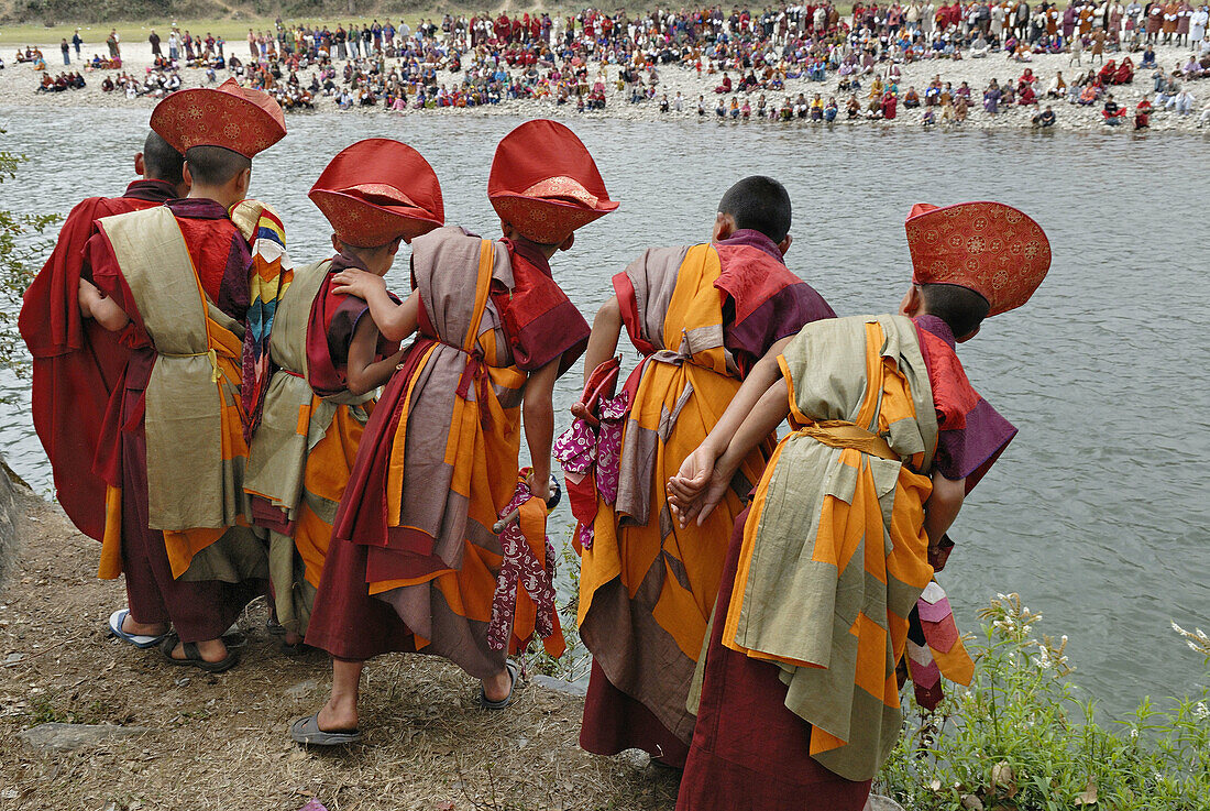 Young novices watching the orange skins thrown into the river which symbolize the relics coveted by the tibetan invaders, punakha serda, punakha, Bhutan