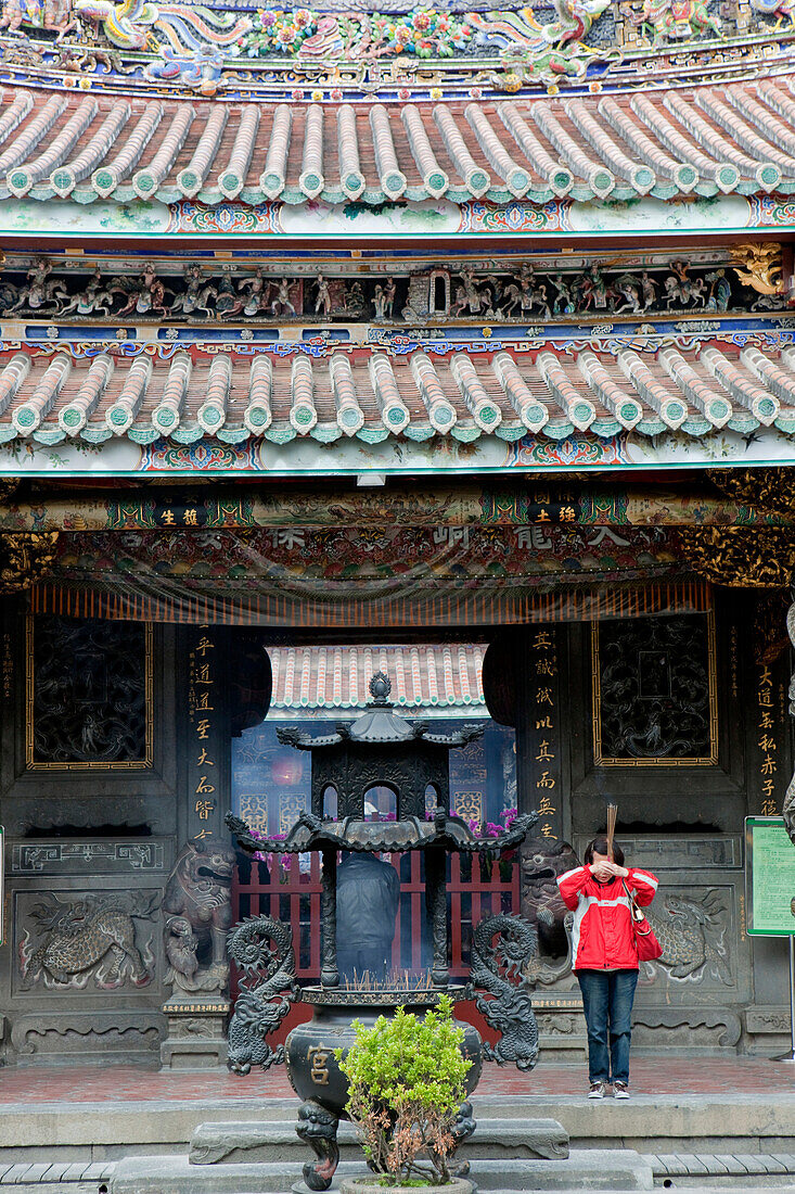 Praying Taoists woman in front of the entrace of Bao-an Temple, Shida district, Taipei, Taiwan, Asia